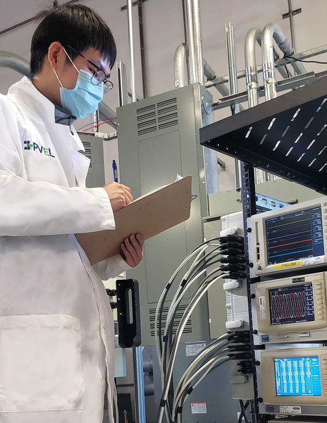 A PVEL lab technician notes power measurements of a solar inverter A PVEL lab technician notes power measurements of a solar inverter