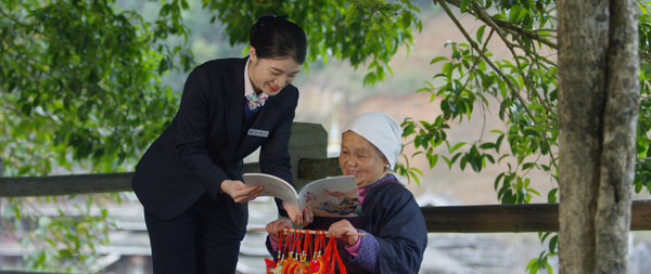 Photo shows an employee of Guilin Bank explains the rural vitalization policies to a villager in rural area of Guangxi. (By Jiang Chen)