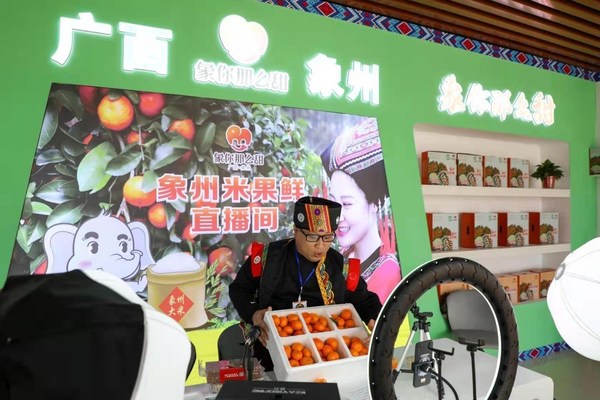 Staff member sell sugar orange via live streaming in Xiangzhou County, south China's Guangxi Zhuang Autonomous Region at the sixth Sugar Orange Festival, Dec. 17, 2021.