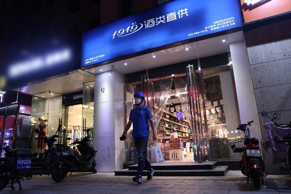 A Dada Now rider is taking beverages from a physical wine store on his way delivering orders to consumers.