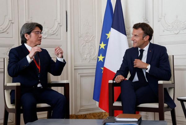 French President Emmanuel Macron (R) speaks with ProLogium CEO Vincent Yang (L) during a meeting as part of the 5th edition of the "Choose France" Business Summit in Versailles, southwest of Paris, on July 11, 2022. Credits: imagery supplied by LUDOVIC MARIN/AFP via Getty Images