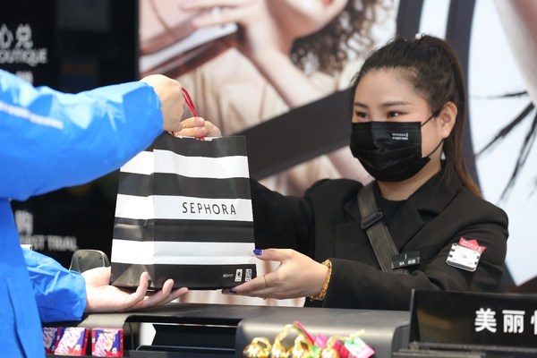 A Dada rider is taking an order at a shop of Sephora.