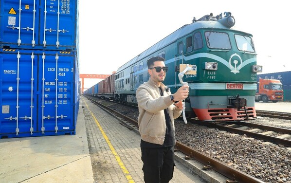 A vlogger from Venezuela records a monologue alongside a China-Europe freight train at the Wuxi West Railway Station Logistics Park.