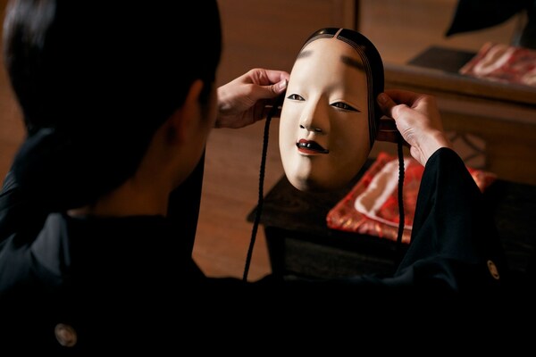 Master of Noh theatre holding a traditional Noh mask, and preparing for the performance.