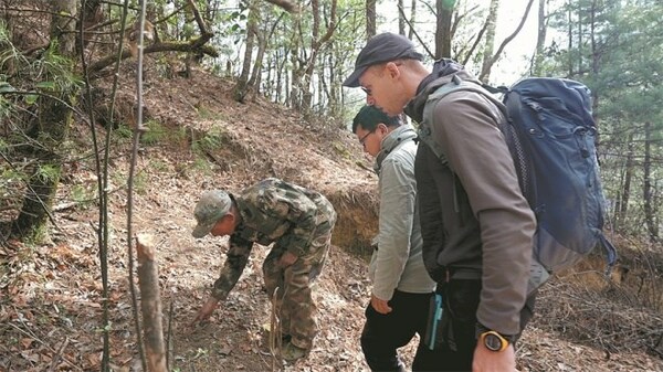 Yu Jianhua (left), a forest ranger at the Baima Snow Mountain National Nature Reserve in Yunnan province, is joined by Lai Jiandong (middle), head of the wildlife protection station at the reserve, and French travel writer Yannick Benichou as they check the feces of Yunnan snub-nosed monkeys to monitor the animals' health in March. [Photo / China Daily]
