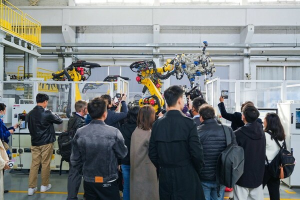 Observers watch industrial robots working based on instructions wirelessly transmitted&nbsp;at high speeds via 5G-Advanced indoor base stations